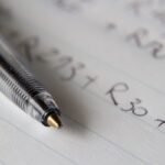 Bolígrafo sobre un papel con números y códigos anotados a mano